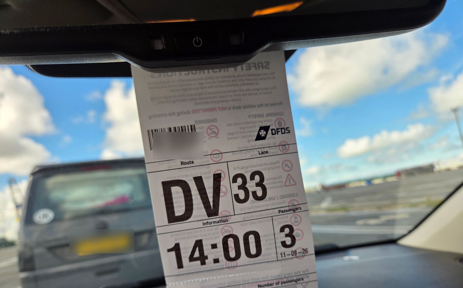 DFDS lane hanger on a rear-view mirror showing lane 33, the 14:00 sailing and three passengers