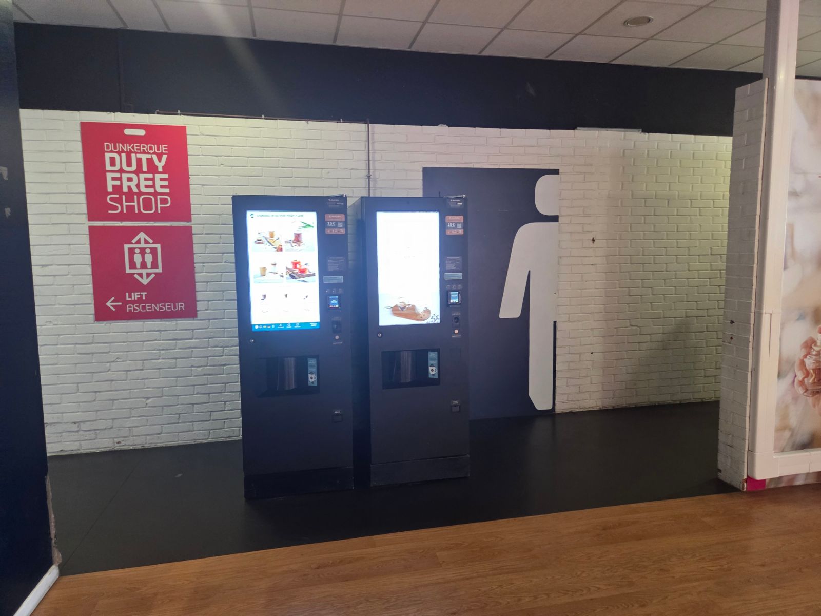 Two coffee vending machines next to the toilets and a duty free sign inside the Dunkirk terminal