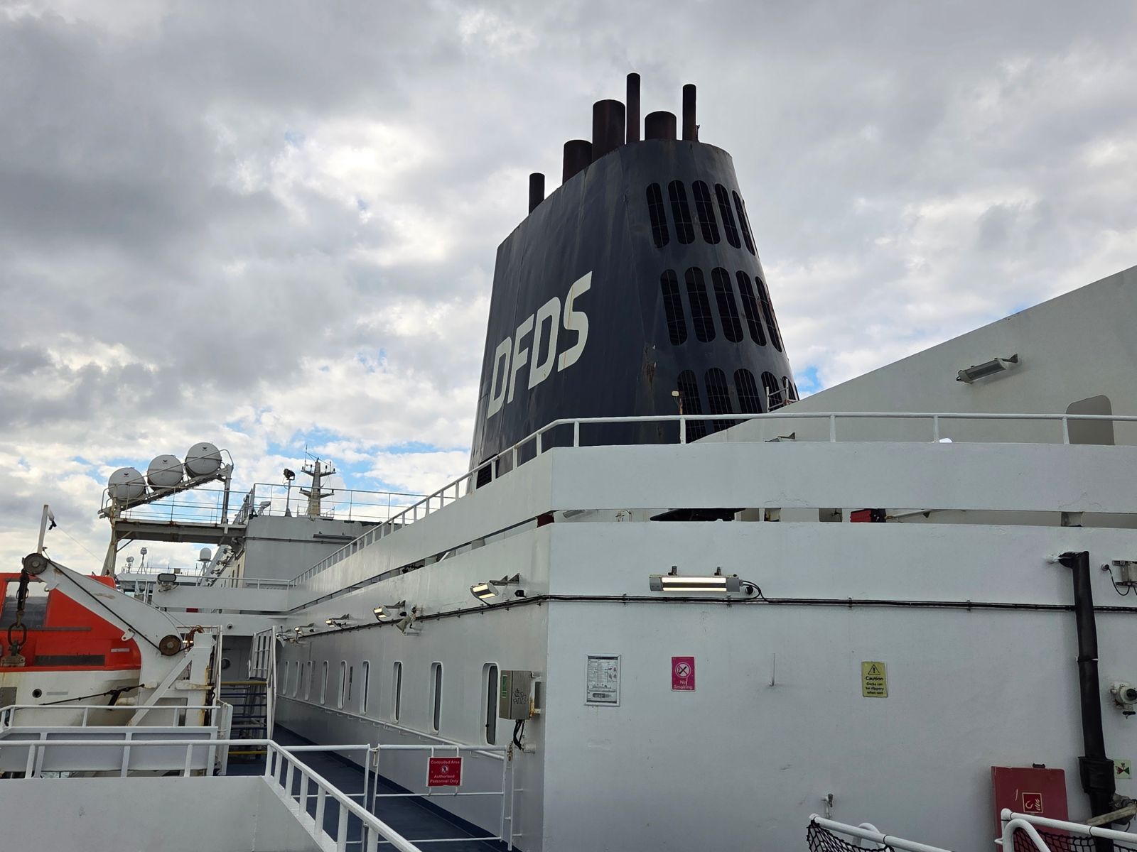 Dark blue DFDS funnel above a white upper deck walkway with lifeboats