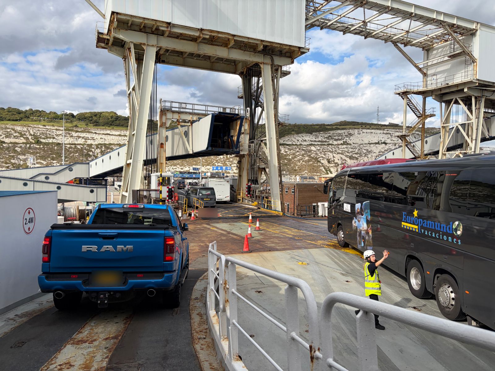 Vehicles driving off Delft Seaways at Dover with chalk cliffs behind and crew directing traffic